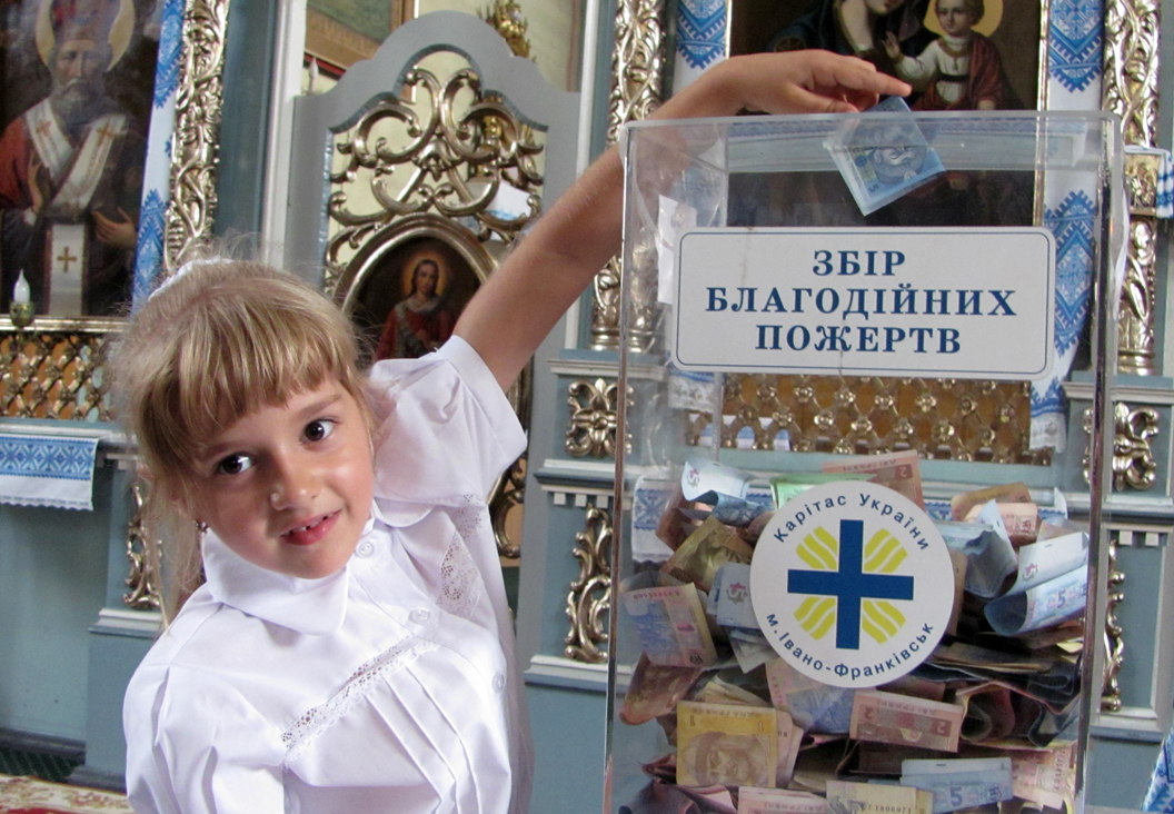 Хлопчик кидає пожертву в скриньку акції «Шкільний портфелик», 2012 рік