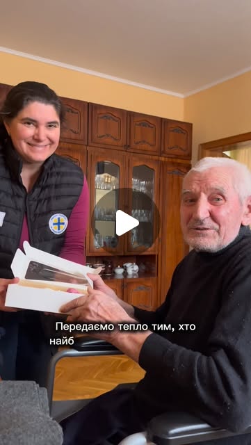 Працівниця Карітасу Івано-Франківськ передає подарунок літньому чоловікові